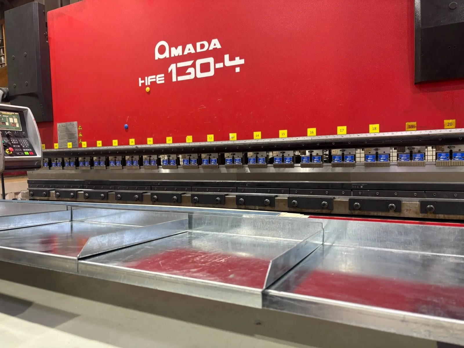 Presse plieuse Amada HFE 130-4 de l'atelier avec des pièces en tôle galvanisée pliées